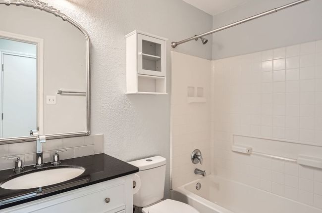 Bathroom featuring toilet, washtub / shower combination, vanity, and a textured wall | Image 20