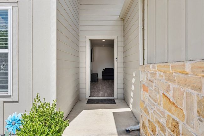 The inviting front entryway, with a stone accent wall and a covered porch area, providing a warm welcome for residents and guests. | Image 23