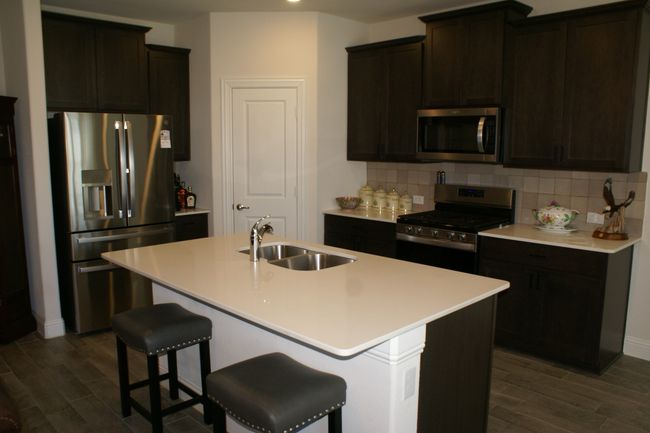 Kitchen with decorative backsplash, dark wood finished floors, appliances with stainless steel finishes, and a sink | Image 16