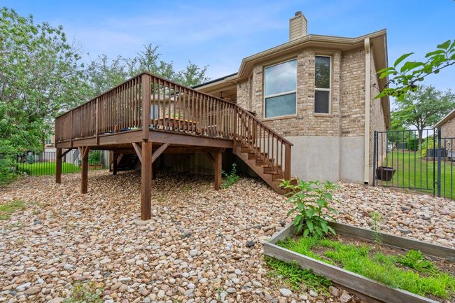 View of yard featuring iron fence, xeriscape backyard, a raised garden bed, large deck with stairs | Image 33