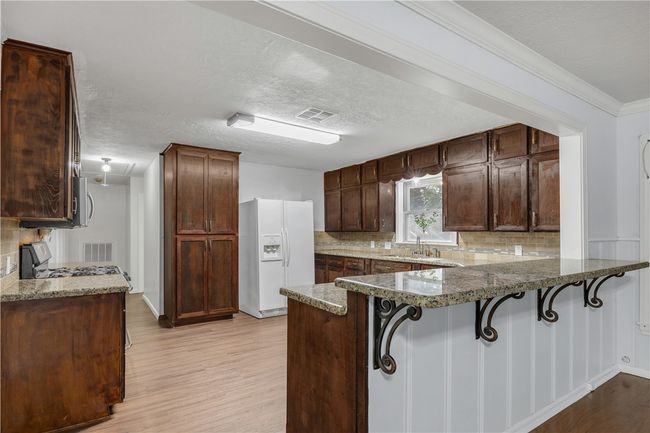 Kitchen with a breakfast bar, light wood-type flooring, tasteful backsplash | Image 8