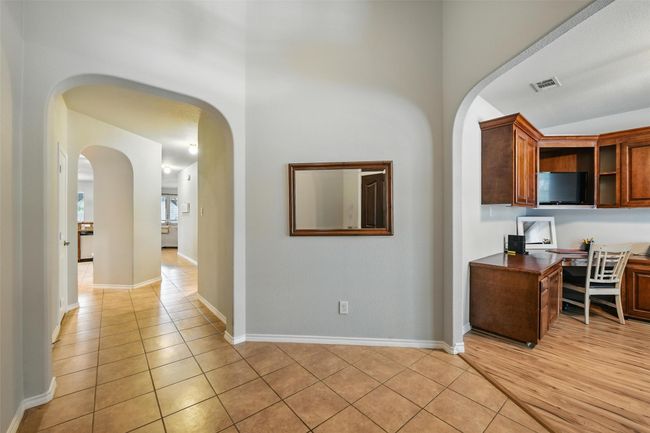 Hallway featuring arched walkways, light tile patterned flooring, and a desk | Image 10