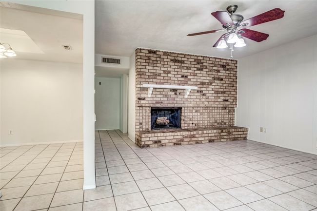 Unfurnished living room featuring a ceiling fan, a brick fireplace, and light tile patterned floors | Image 17