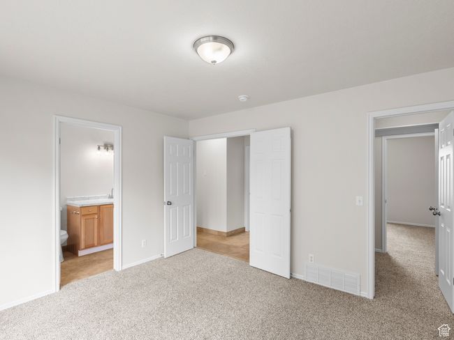 Unfurnished bedroom featuring light carpet, baseboards, and connected bathroom | Image 17