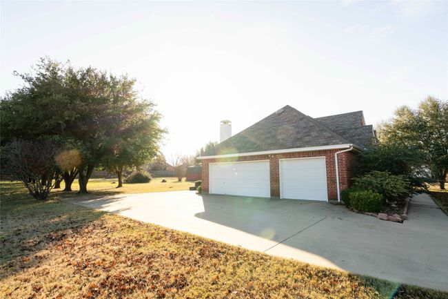 View of side of property with concrete driveway, brick siding, a chimney, and a shingled roof | Image 27