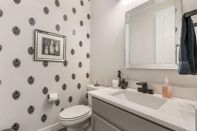This photo showcases a stylish bathroom with patterned wallpaper, a modern sink, and a large framed mirror. | Image 39