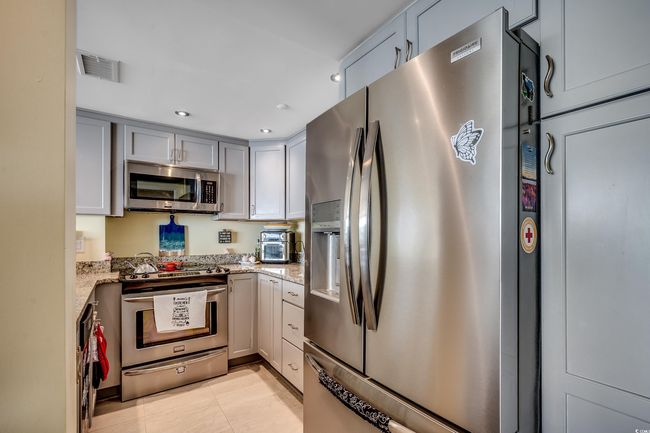 Kitchen with appliances with stainless steel finishes, light stone countertops, gray cabinetry, recessed lighting, and light tile patterned floors | Image 5