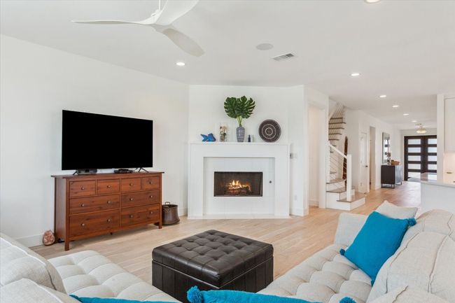 Living area featuring ceiling fan, light wood-style floors, recessed lighting, stairway, and a tile fireplace | Image 9