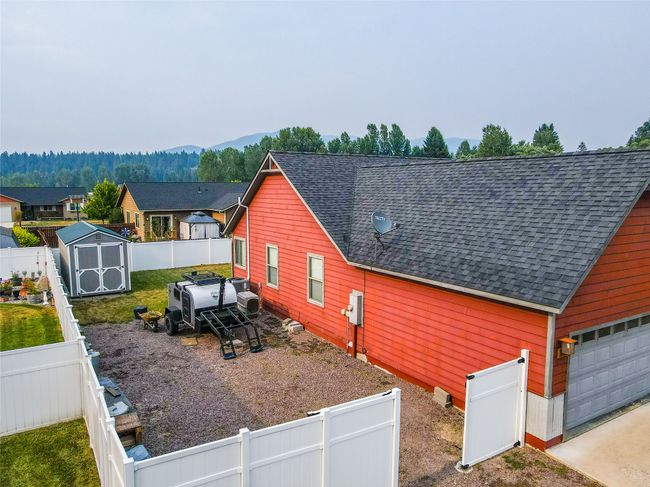 View of home's exterior featuring roof with shingles, a fenced backyard, and a storage shed | Image 17
