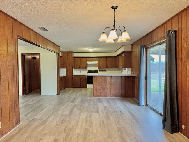 Kitchen featuring light hardwood / wood-style flooring, an inviting chandelier, black / electric stove, decorative light fixtures, and kitchen peninsula | Image 16