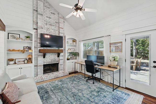 Office area featuring plenty of natural light, a brick fireplace, built in features, wood finished floors, and high vaulted ceiling | Image 12