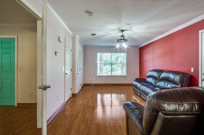 Living area with wood finished floors, a chandelier, and ornamental molding | Image 6