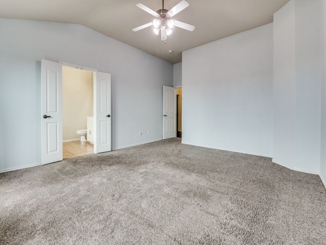 Unfurnished bedroom with lofted ceiling, connected bathroom, baseboards, and carpet floors | Image 18