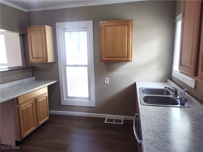 Kitchen with a sink, baseboards, dark wood finished floors, light countertops, and ornamental molding | Image 24