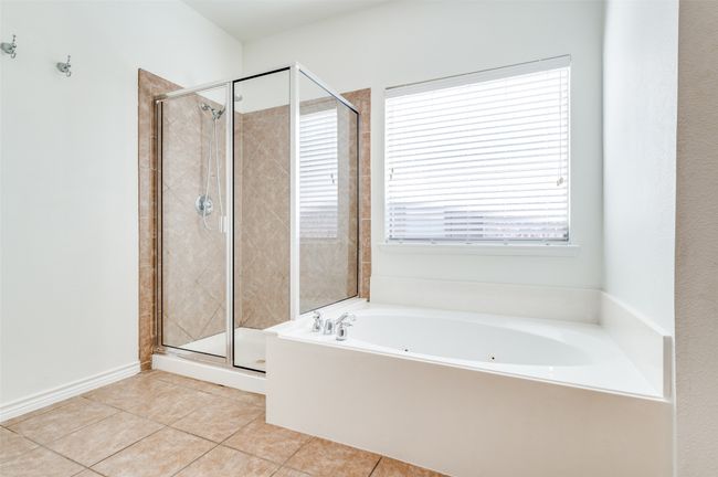 This spacious primary bathroom is a serene retreat, featuring a luxurious soaker tub perfect for unwinding after a long day. A double vanity provides ample space for two, combining style and functionality. With its generous layout and elegant finishes, this bath is designed for both comfort and convenience. | Image 18