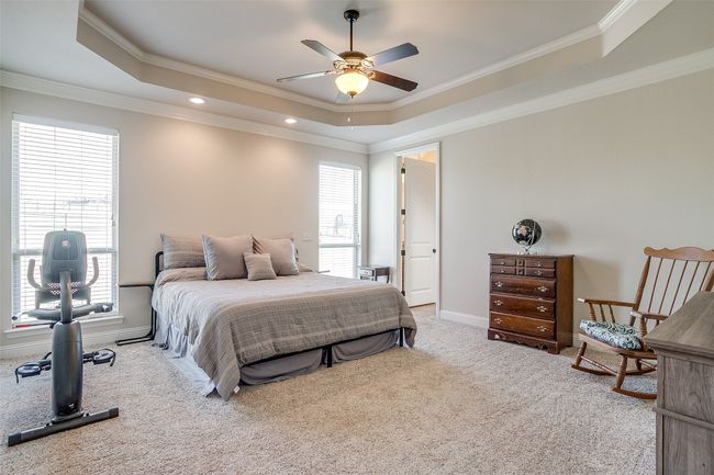 Bedroom with ornamental molding, carpet floors, a raised ceiling, and multiple windows | Image 14