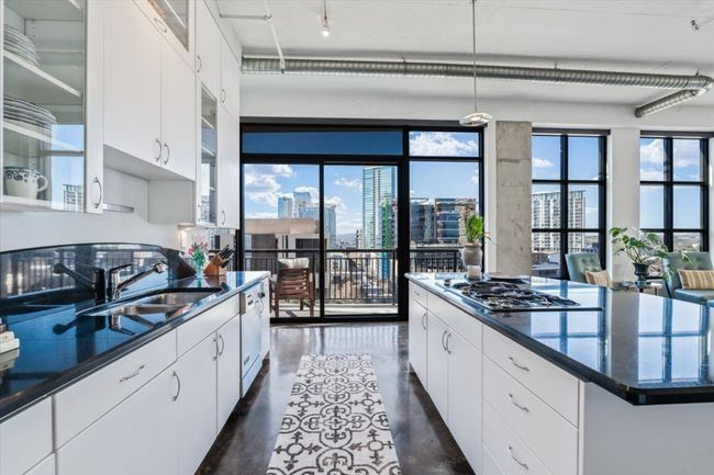 Kitchen with Ink granite countertops, a view of city, concrete floors, and white cabinets | Image 10