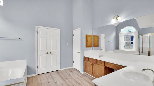 Full master bath featuring double vanity, vinyl plank floors, a stall shower, a bath, and high vaulted ceiling | Image 29