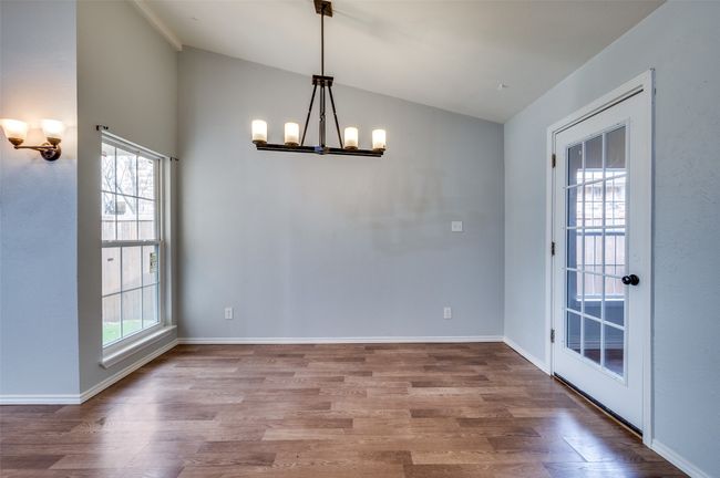 Unfurnished dining area with lofted ceiling, a chandelier, and wood finished floors | Image 5