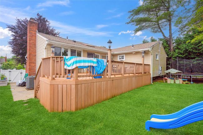 Back of property featuring a trampoline, a wooden deck, a chimney, and a gate | Image 22