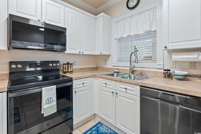 Kitchen with appliances with stainless steel finishes, ornamental molding, light tile patterned floors, white cabinetry, and light countertops | Image 17