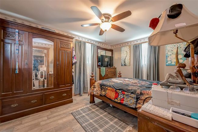 Spacious and light-filled, this primary bedroom features large windows and an overhead fan for comfort. Double swinging doors add architectural flair and a sense of transition into the private bath. | Image 22