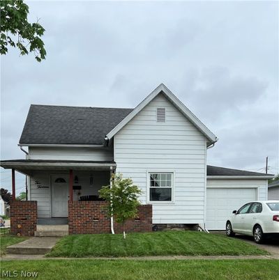 View of front of property with a garage, a front lawn, and covered porch | Image 1