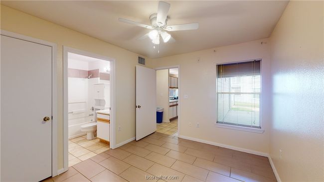 Unfurnished bedroom with connected bathroom, light tile patterned flooring, and ceiling fan | Image 12