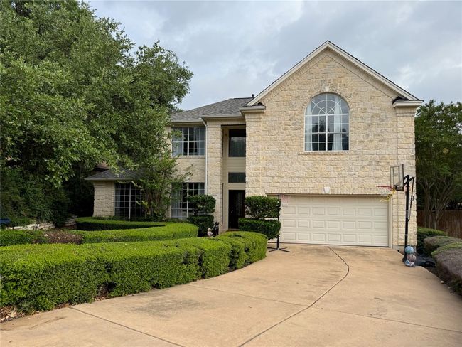 View of front facade with concrete driveway, an attached garage, a shingled roof, and stone siding | Image 36