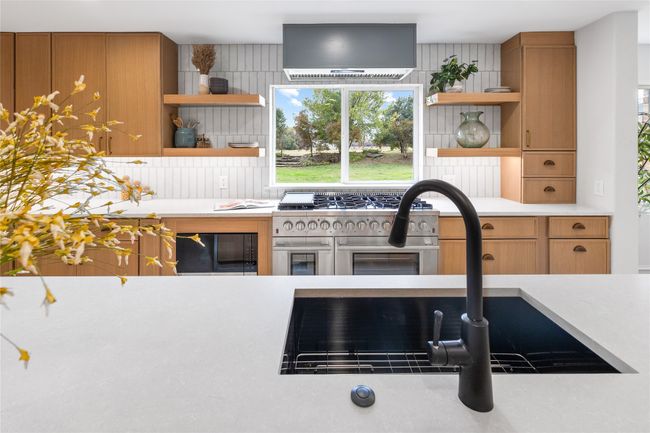 Kitchen featuring open shelves, double oven range, wall chimney range hood, light countertops, and brown cabinetry | Image 16