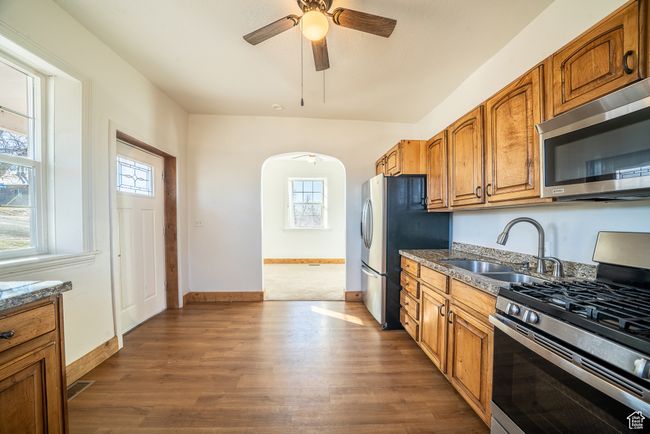 Kitchen featuring dark wood-type flooring, arched walkways, stainless steel appliances, and a sink | Image 7