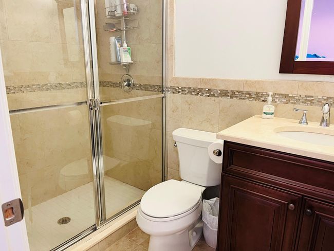 Full bath featuring vanity, a shower stall, tile walls, wainscoting, and tile patterned flooring | Image 13