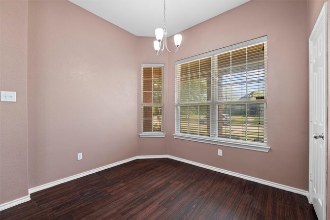 Unfurnished room with a notable chandelier, dark wood-style floors, and baseboards | Image 20