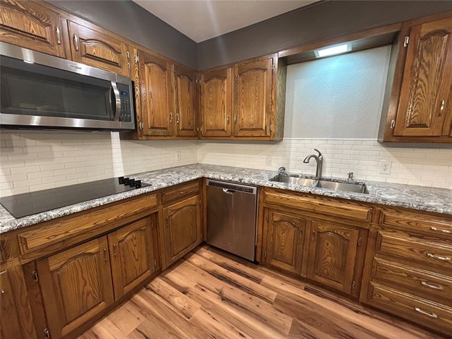 Kitchen with stainless steel appliances, decorative backsplash, light wood-style floors, and brown cabinets | Image 18
