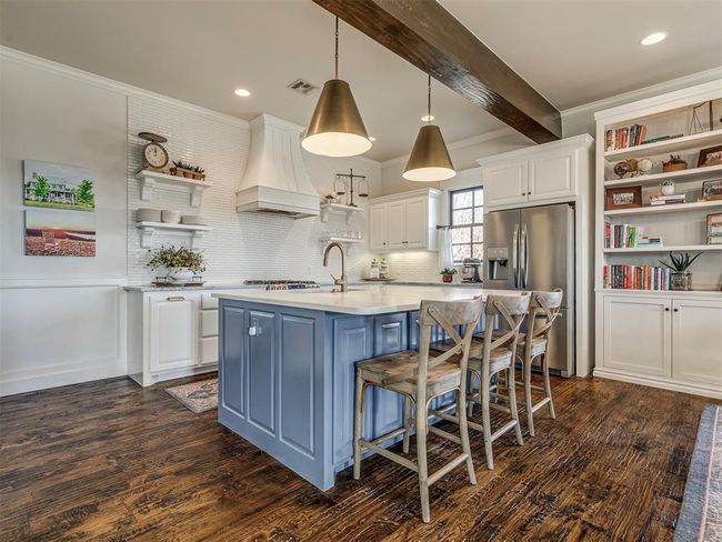 Kitchen featuring stainless steel fridge, custom exhaust hood, light countertops, open shelves, and a sink | Image 4
