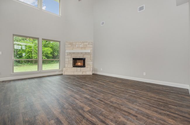 Unfurnished living room with dark wood finished floors, a towering ceiling, baseboards, and a fireplace | Image 6