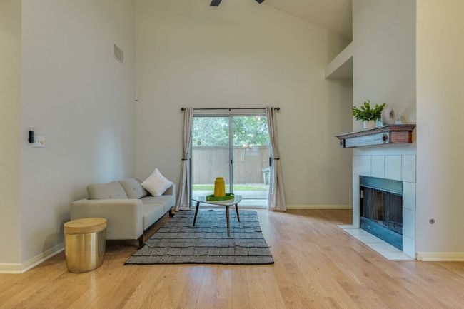 Living area featuring high vaulted ceiling, wood finished floors, a fireplace, and ceiling fan | Image 10