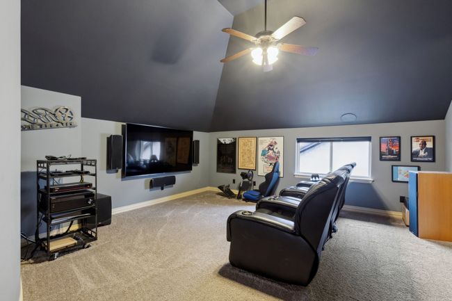 Carpeted cinema featuring ceiling fan, lofted ceiling, and baseboards, flush mounted ceilings and rear speakers paint matched | Image 25