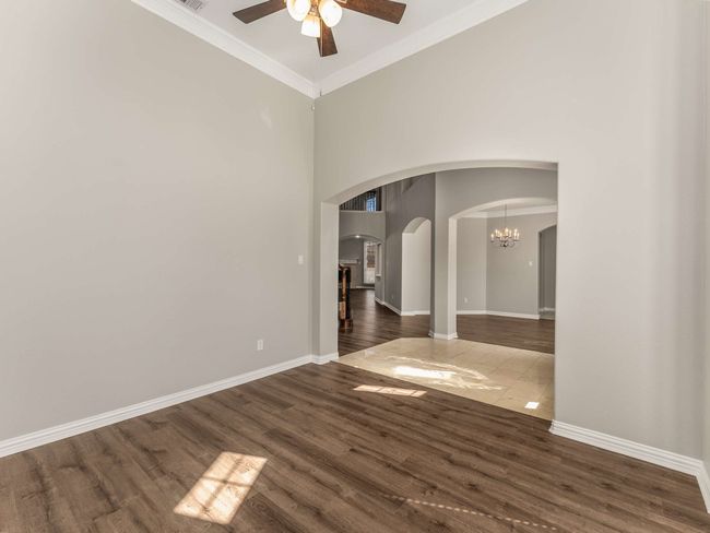 Spare room with wood finished floors, arched walkways, ornamental molding, and ceiling fan with notable chandelier | Image 22