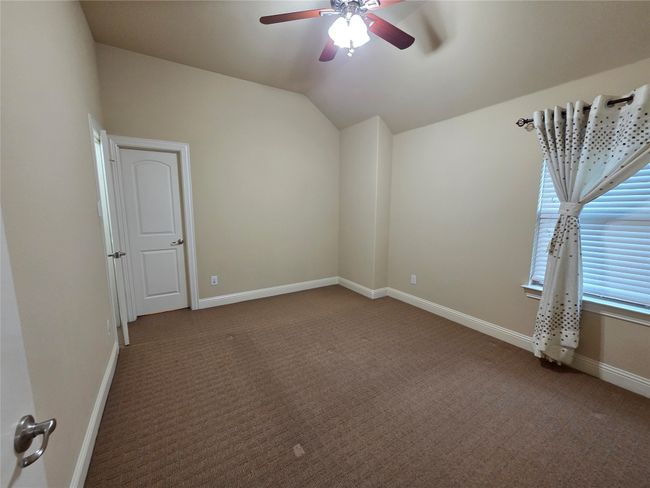 Carpeted empty room with a ceiling fan and vaulted ceiling | Image 29