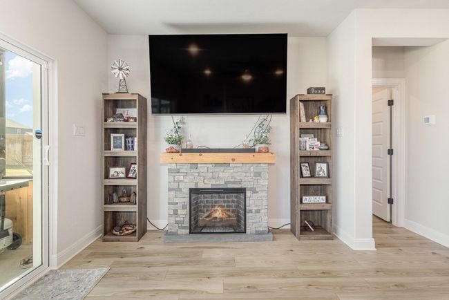 Living area with wood finished floors, a stone fireplace, and baseboards | Image 4
