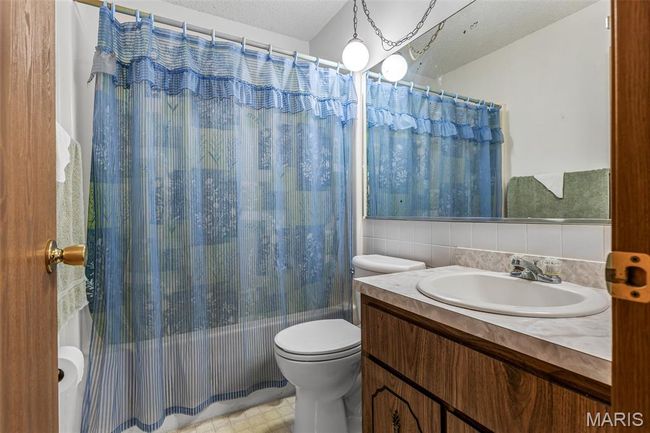 Bathroom with toilet, shower / bath combo with shower curtain, vanity, and tasteful backsplash | Image 30