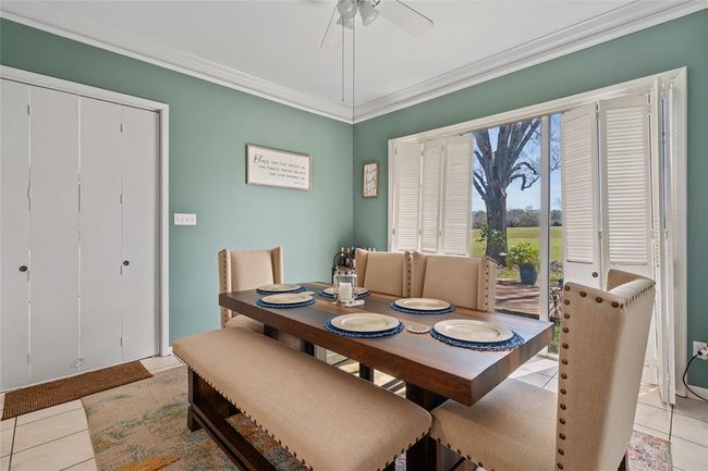 This bright and airy dining area offers a welcoming space to enjoy meals while taking in picturesque views through expansive windows. The classic plantation shutters allow for adjustable natural light, while the neutral tones and crown molding add a touch of elegance. | Image 16