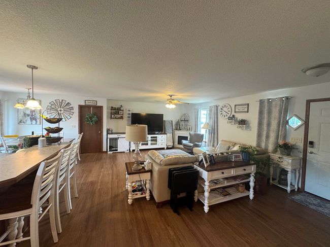 Living room with dark wood-style flooring, a textured ceiling, and ceiling fan | Image 15