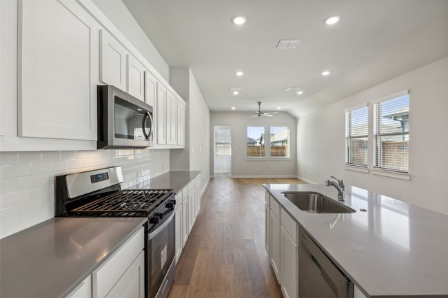 Kitchen featuring stainless steel appliances, a sink, decorative backsplash, wood finished floors, and recessed lighting | Image 5