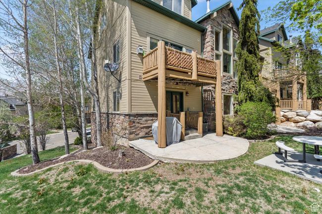 Rear view of house with a patio area, stone siding, and a lawn | Image 21