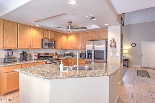 Kitchen with appliances with stainless steel finishes, a tray ceiling, light tile patterned flooring, recessed lighting, and a kitchen island with sink | Image 30