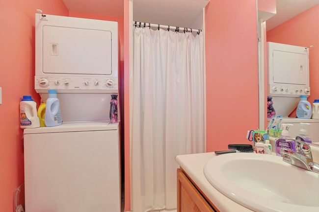Bathroom featuring curtained shower, stacked washing maching and dryer, and vanity | Image 10
