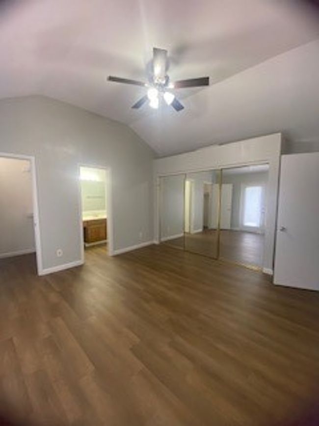Unfurnished bedroom featuring a closet, lofted ceiling, wood finished floors, baseboards, and ceiling fan | Image 26