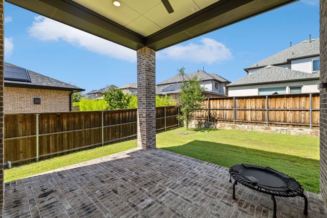 Fenced backyard with a patio area, ceiling fan, and a residential view | Image 37